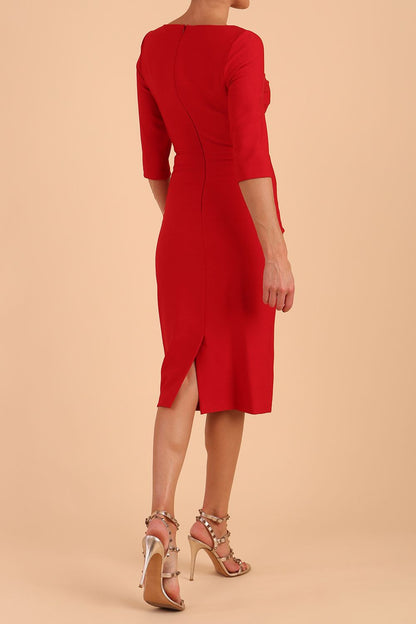 model wearing seed couture royale pencil skirt dress with pleating across the tummy area with rounded neckline with a split in the middle and 3 4 sleeve in Salsa Red colour front side