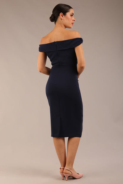 brunette model wearing a diva catwalk cloud pencil fitted flattering dress off shoulder sleeveless with detail with pleating around the front in navy blue front