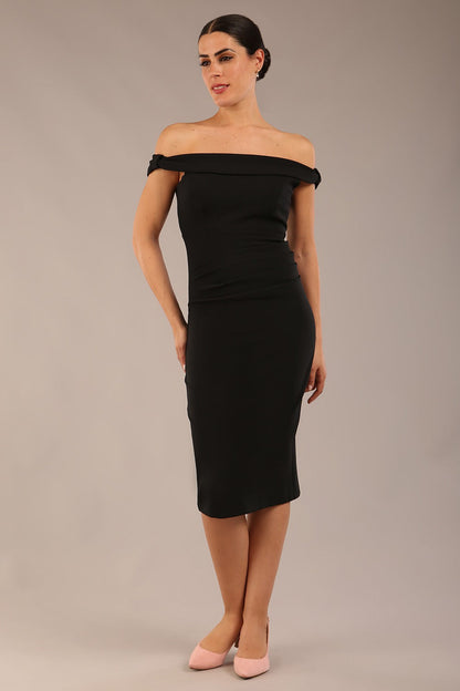 brunette model wearing a diva catwalk cloud pencil fitted flattering dress off shoulder sleeveless with detail with pleating around the front in black front