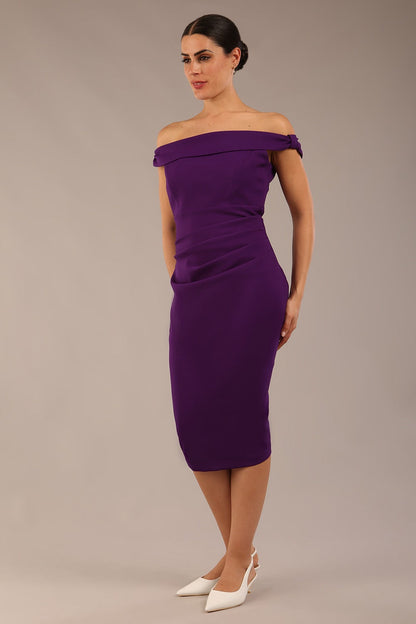 brunette model wearing a diva catwalk cloud pencil fitted flattering dress off shoulder sleeveless with detail with pleating around the front in deep purple front