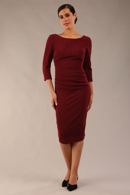 model is wearing diva catwalk polly sleeved pencil dress with low rounded neckline at the back in Cabaret Burgundy side