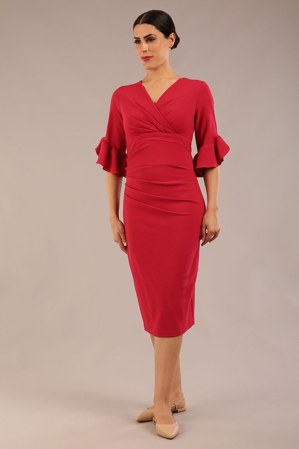 brunette model is wearing diva catwalk hollie pencil dress with frilled flute sleeve and low v-neck cut in dazzle pink front 