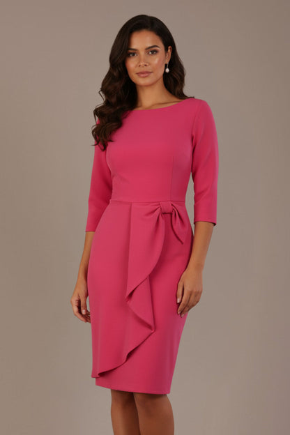 model is wearing diva catwalk jacky dress with rounded neckline 3/4 sleeve and bow detail on the waist in honeysuckle pink front view