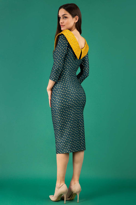 A brunette model is wearing a bi stretch pencil print mustard green dress by diva catwalk back image