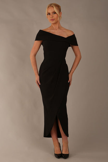 brunette model wearing diva catwalk vegas calf-length black midaxi dress with wide bardot neckline and open shoulders with a large opening at the front of the skirt with pleating coming down long skirt front (Black)
