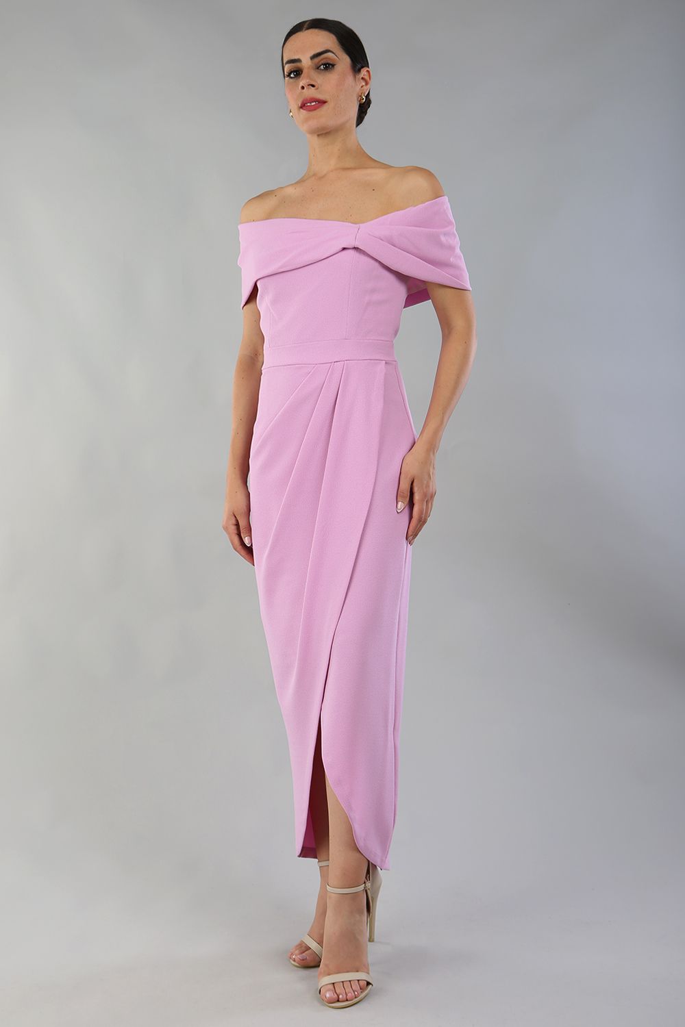 brunette model wearing diva catwalk vegas calf length dawn pink midaxi dress with wide bardot neckline and open shoulders with a large opening at the front of the skirt with pleating coming down long skirt front (Dawn Pink)