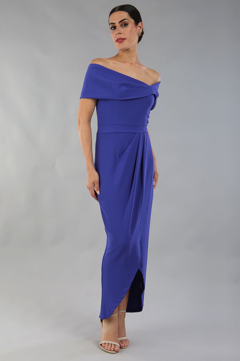 model wearing diva catwalk vegas calf length spectrum indigo midaxi dress with wide bardot neckline and open shoulders with a large opening at the front of the skirt with pleating coming down long skirt front (Spectrum Indigo)