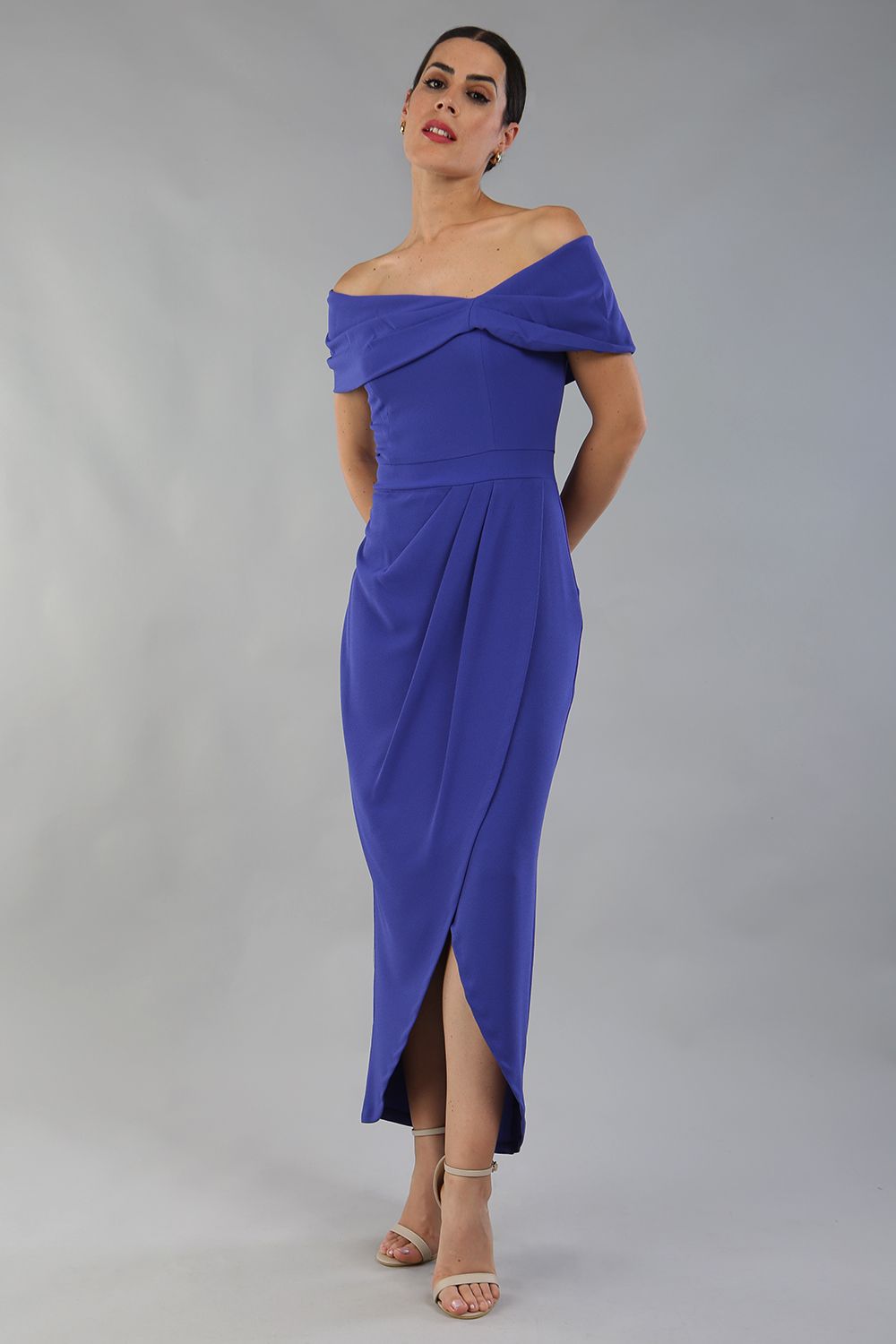 model wearing diva catwalk vegas calf length spectrum indigo midaxi dress with wide bardot neckline and open shoulders with a large opening at the front of the skirt with pleating coming down long skirt front (Spectrum Indigo)
