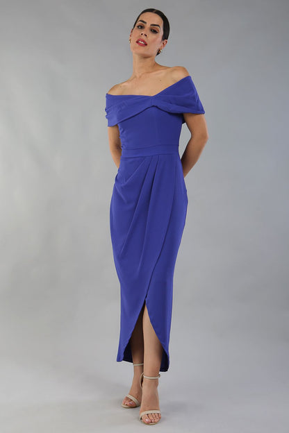 model wearing diva catwalk vegas calf length spectrum indigo midaxi dress with wide bardot neckline and open shoulders with a large opening at the front of the skirt with pleating coming down long skirt front (Spectrum Indigo)