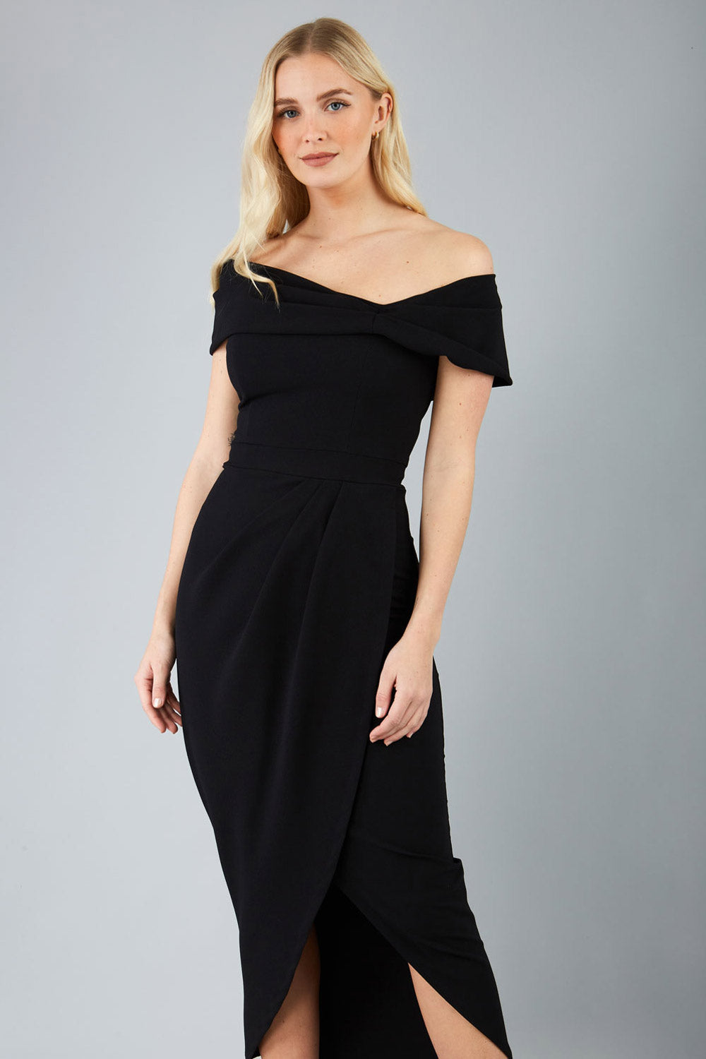 brunette model wearing diva catwalk vegas calf-length black midaxi dress with wide bardot neckline and open shoulders with a large opening at the front of the skirt with pleating coming down long skirt front (Black)