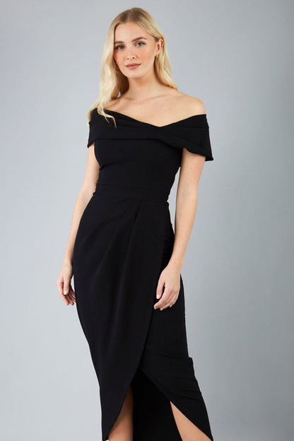 brunette model wearing diva catwalk vegas calf-length black midaxi dress with wide bardot neckline and open shoulders with a large opening at the front of the skirt with pleating coming down long skirt front (Black)