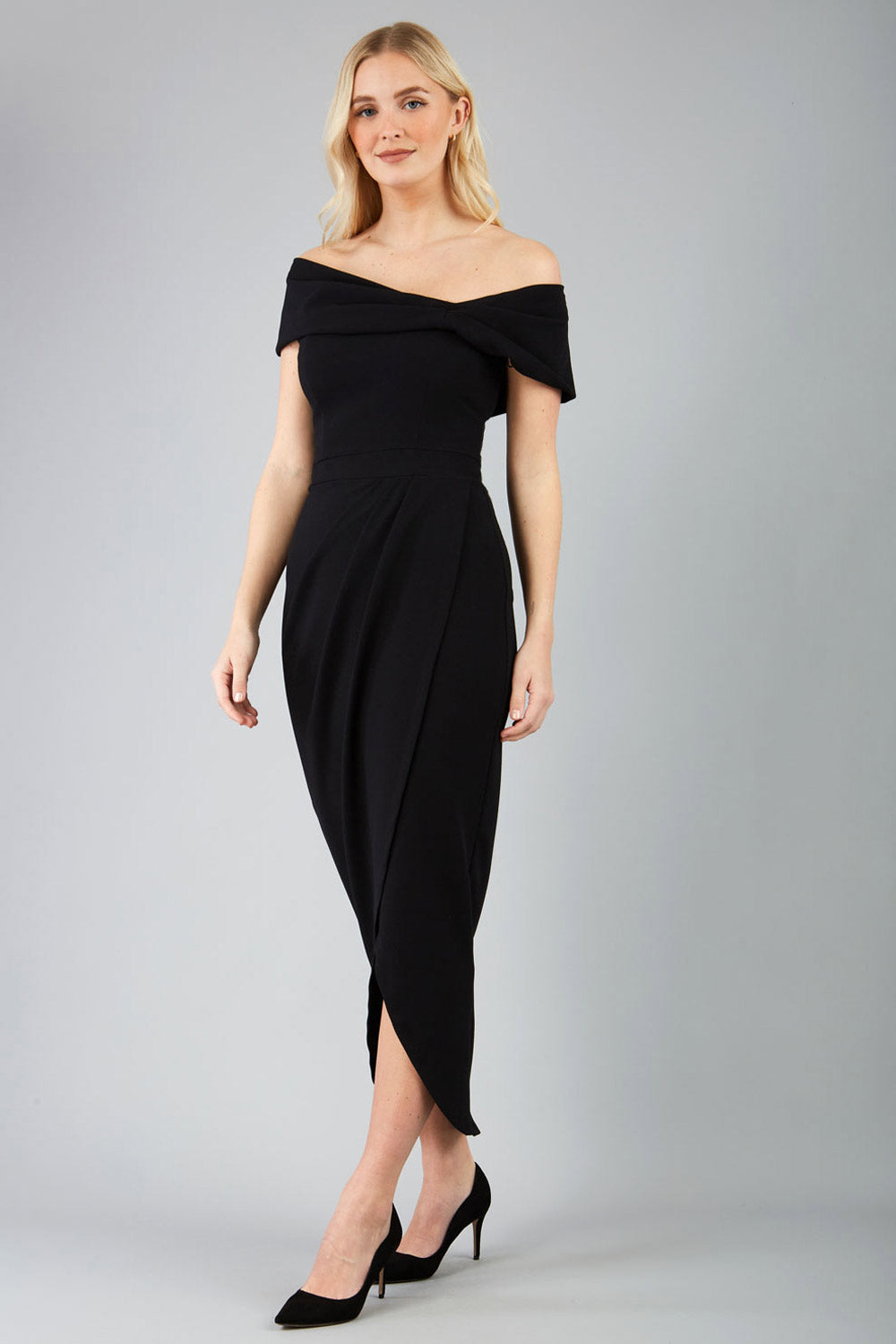 brunette model wearing diva catwalk vegas calf-length black midaxi dress with wide bardot neckline and open shoulders with a large opening at the front of the skirt with pleating coming down long skirt front (Black)