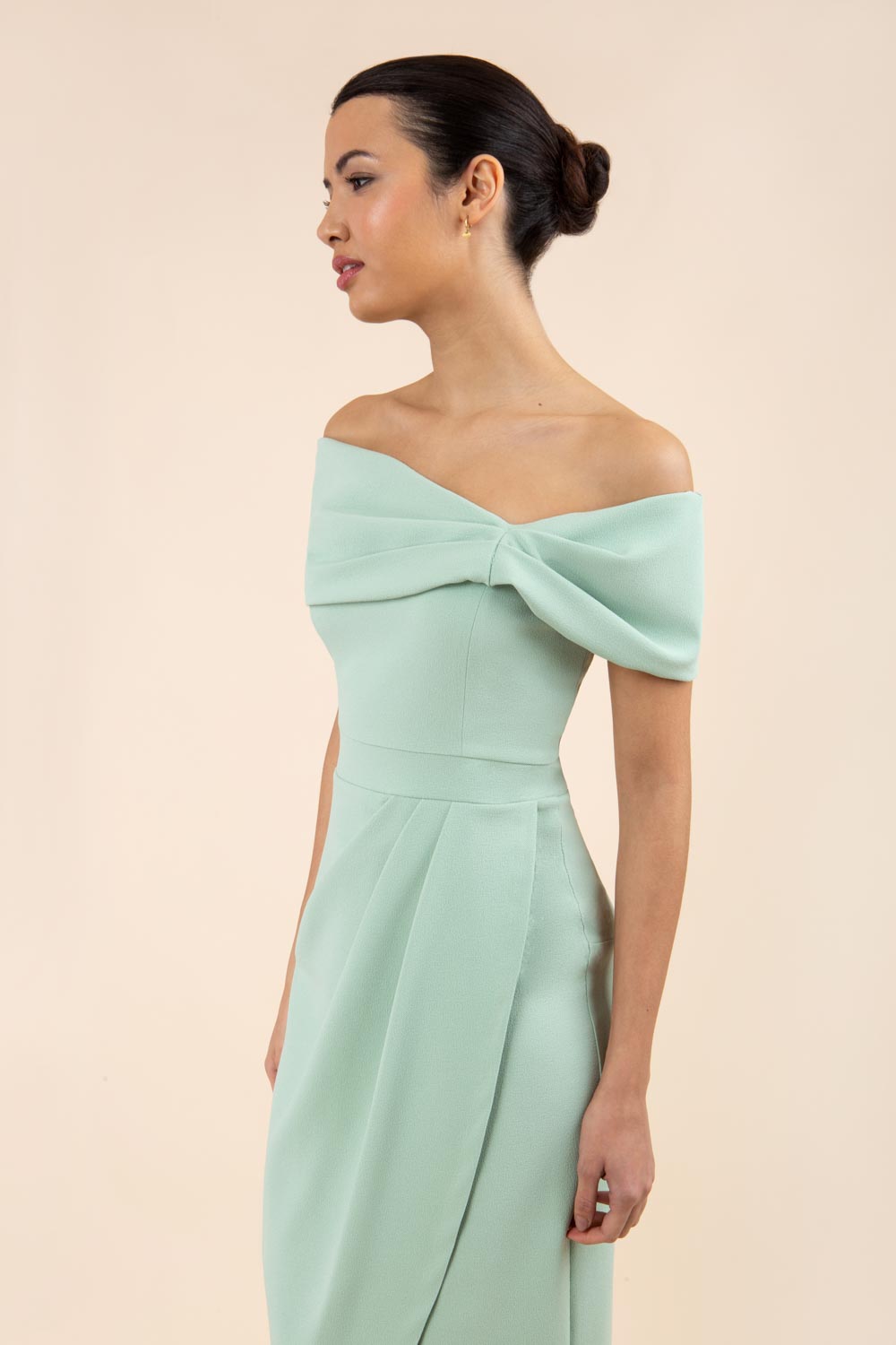brunette model wearing diva catwalk vegas calf length pale deco green midaxi dress with wide bardot neckline and open shoulders with a large opening at the front of the skirt with pleating coming down long skirt front (Deco Green)