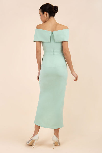 brunette model wearing diva catwalk vegas calf length pale green midaxi dress with wide bardot neckline and open shoulders with a large opening at the front of the skirt with pleating coming down long skirt back (Deco Green)