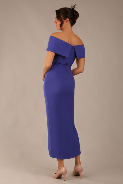 model wearing diva catwalk vegas calf length spectrum indigo midaxi dress with wide bardot neckline and open shoulders with a large opening at the front of the skirt with pleating coming down long skirt front (Spectrum Indigo)