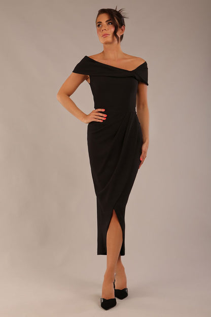 brunette model wearing diva catwalk vegas calf-length black midaxi dress with wide bardot neckline and open shoulders with a large opening at the front of the skirt with pleating coming down long skirt front (Black)