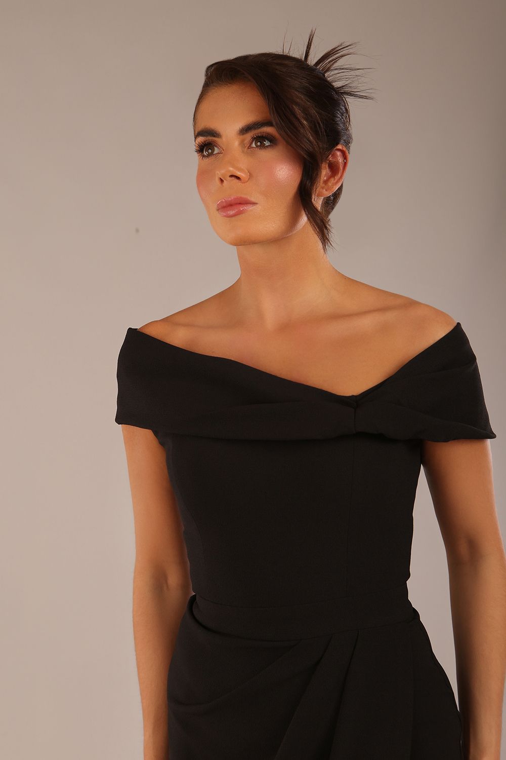 brunette model wearing diva catwalk vegas calf-length black midaxi dress with wide bardot neckline and open shoulders with a large opening at the front of the skirt with pleating coming down long skirt front (Black)