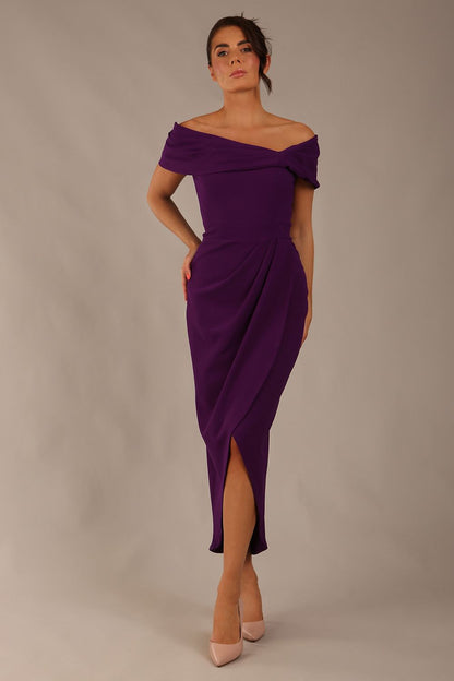 brunette model wearing diva catwalk vegas calf length passion purple midaxi dress with wide bardot neckline and open shoulders with a large opening at the front of the skirt with pleating coming down long skirt front (Passion Purple)