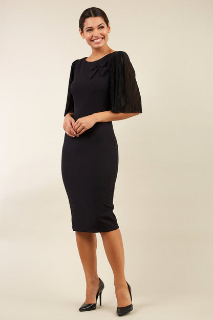 brunette model is wearing diva catwalk black pencil black dress with  bow front image