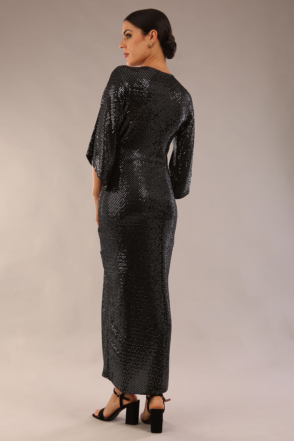 Brunette model wearing diva catwalk Glitterati Midaxi Sparkle Dress in Black in Jersey sparkle and ITY lining with wrap dress style and 3/4 length bell sleeves front side