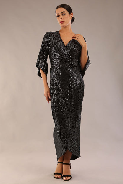Brunette model wearing diva catwalk Glitterati Midaxi Sparkle Dress in Black in Jersey sparkle and ITY lining with wrap dress style and 3/4 length bell sleeves front side