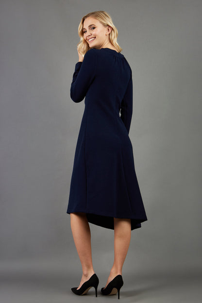 blonde model is wearing diva catwalk dartington asymmetric skirt midaxi long sleeve dress with rounded pleated neckline a-line style in navy blue front