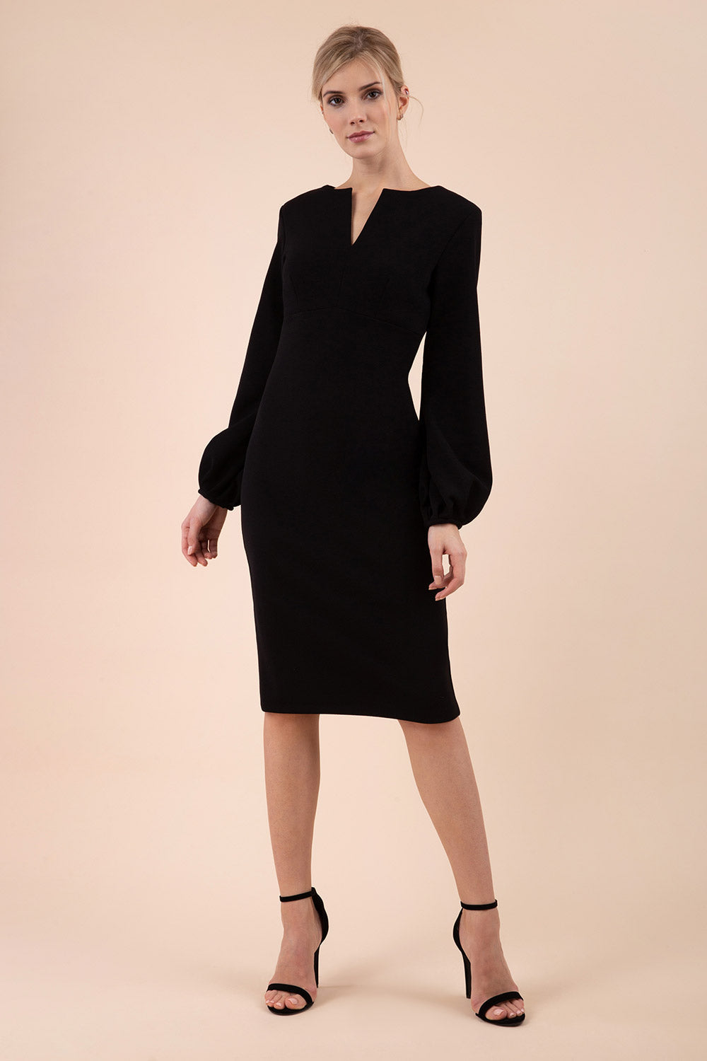 Blonde model wearing Diva Catwalk Praktica long puffed bishop sleeves knee length empire line pencil dress with round neckline with a slit cut in the middle in Black front