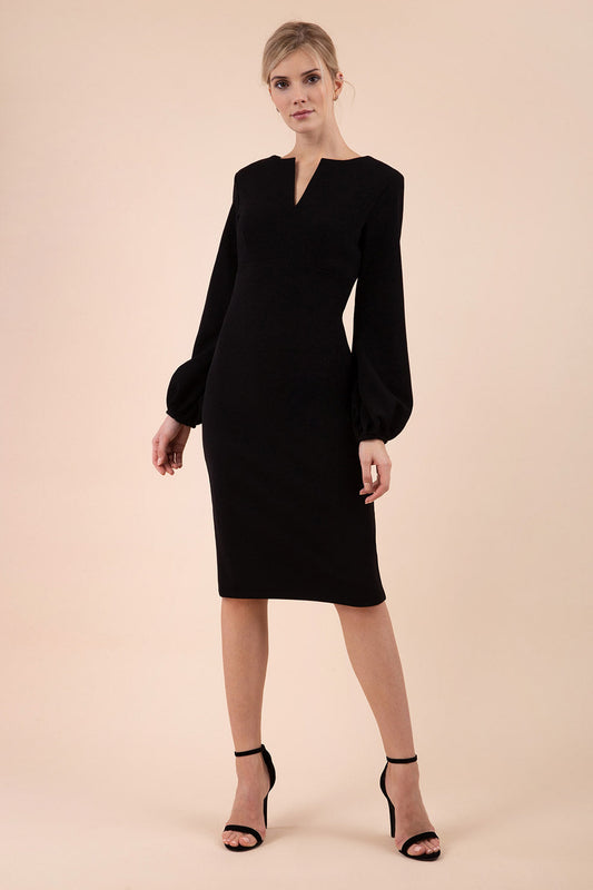 Blonde model wearing Diva Catwalk Praktica long puffed bishop sleeves knee length empire line pencil dress with round neckline with a slit cut in the middle in Black front