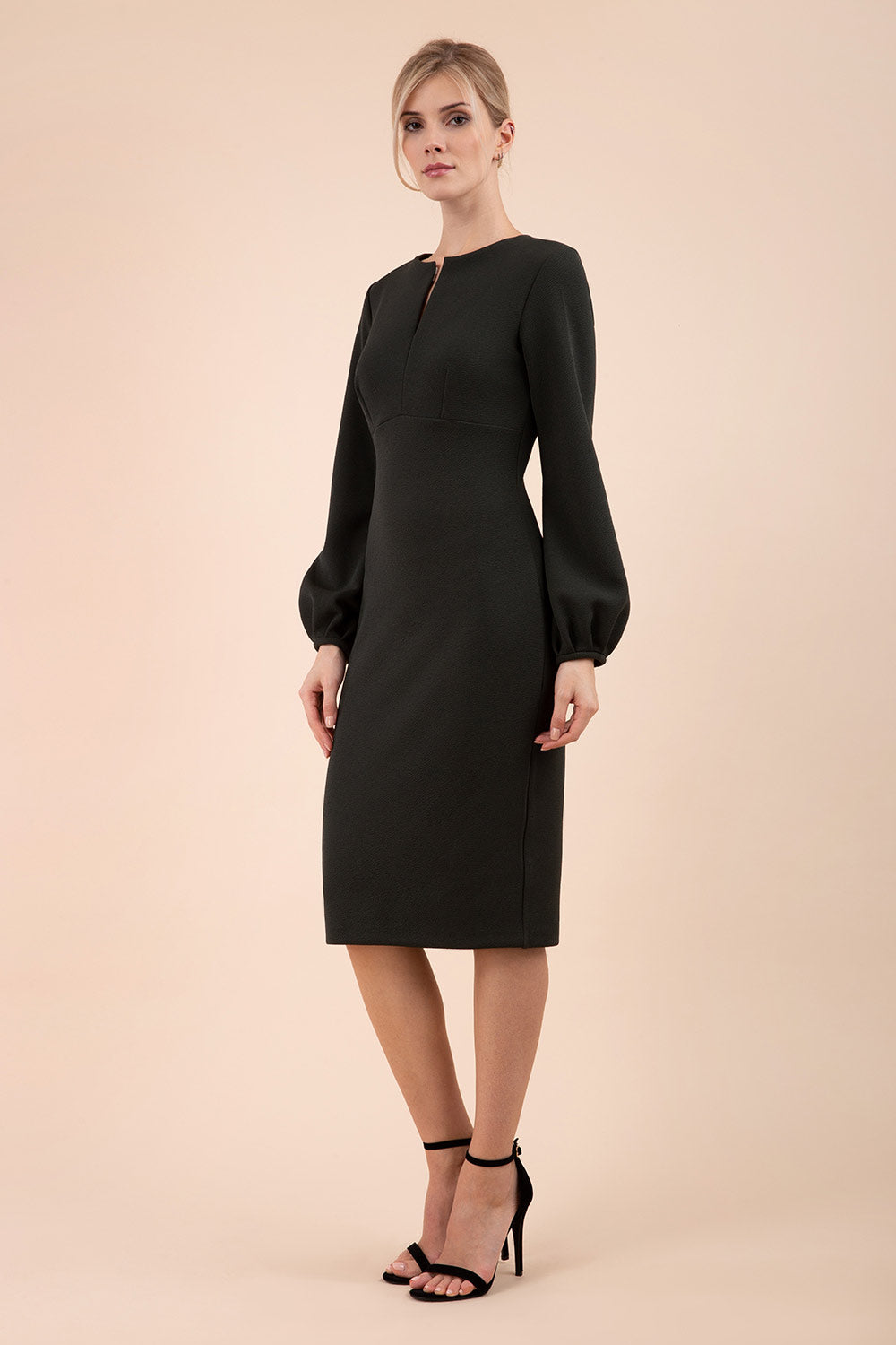 Blonde model wearing Diva Catwalk Praktica long puffed bishop sleeves knee length empire line pencil dress with round neckline with a slit cut in the middle in Black front