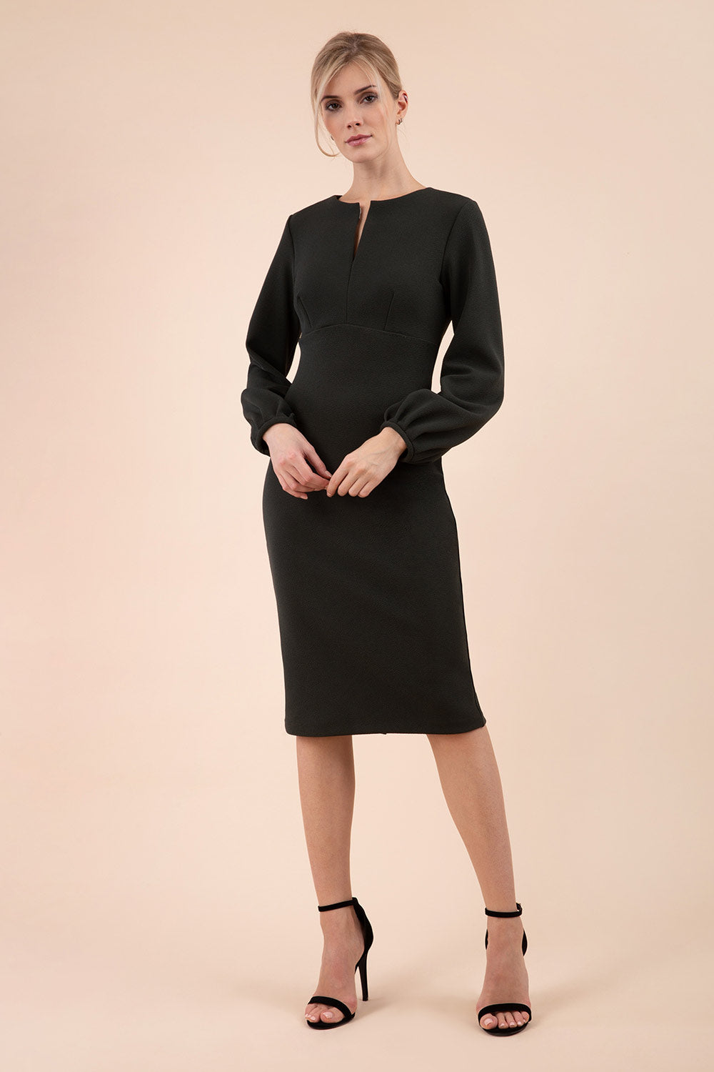 Blonde model wearing Diva Catwalk Praktica long puffed bishop sleeves knee length empire line pencil dress with round neckline with a slit cut in the middle in Black front