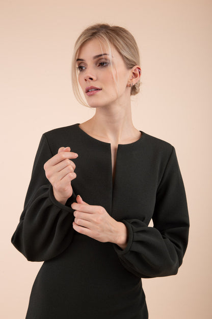 Blonde model wearing Diva Catwalk Praktica long puffed bishop sleeves knee length empire line pencil dress with round neckline with a slit cut in the middle in Black front