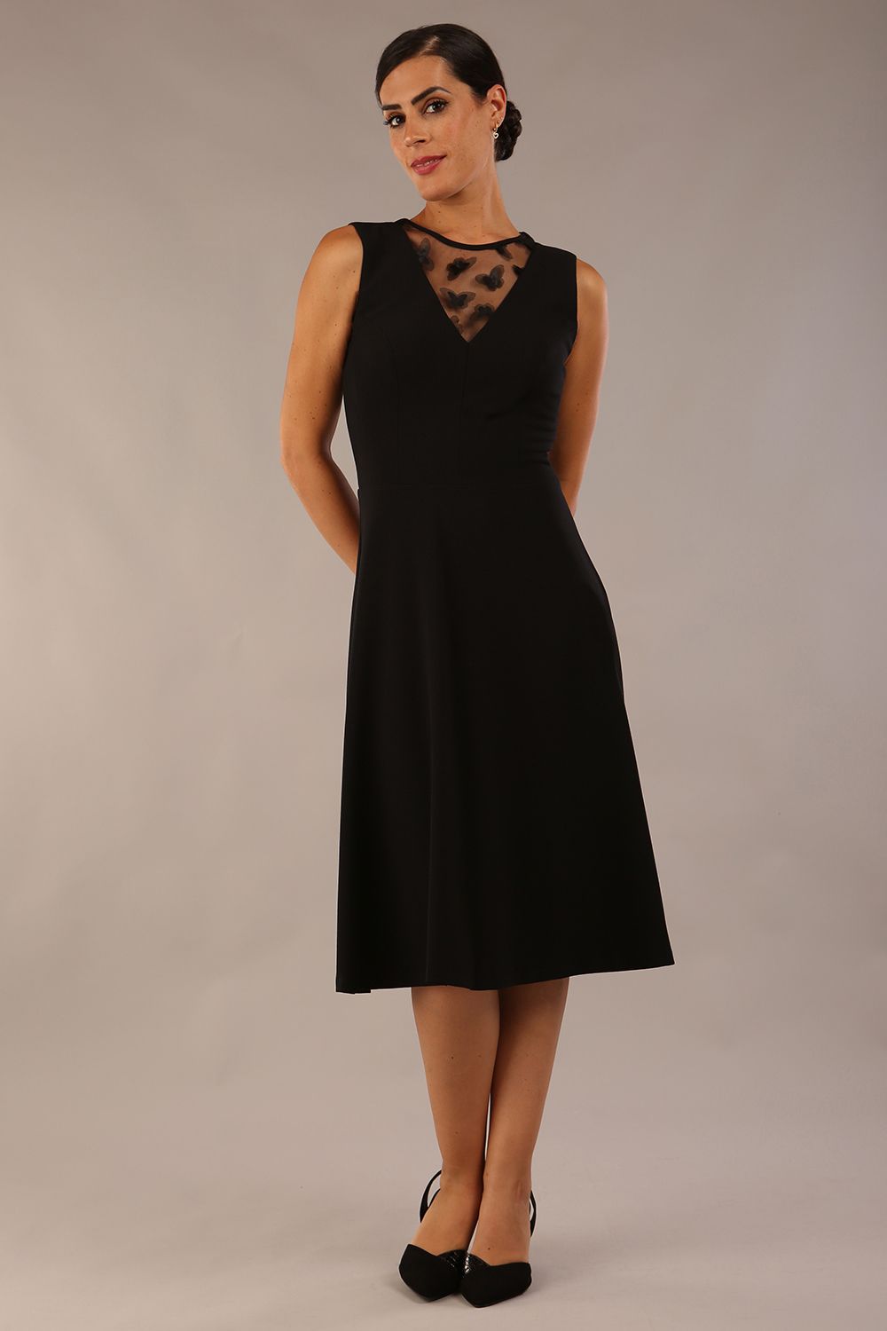 model wearing a Diva Catwalk Patina A-line Swing Sleeveless dress with v-neckline with butterfly detail in Black close up