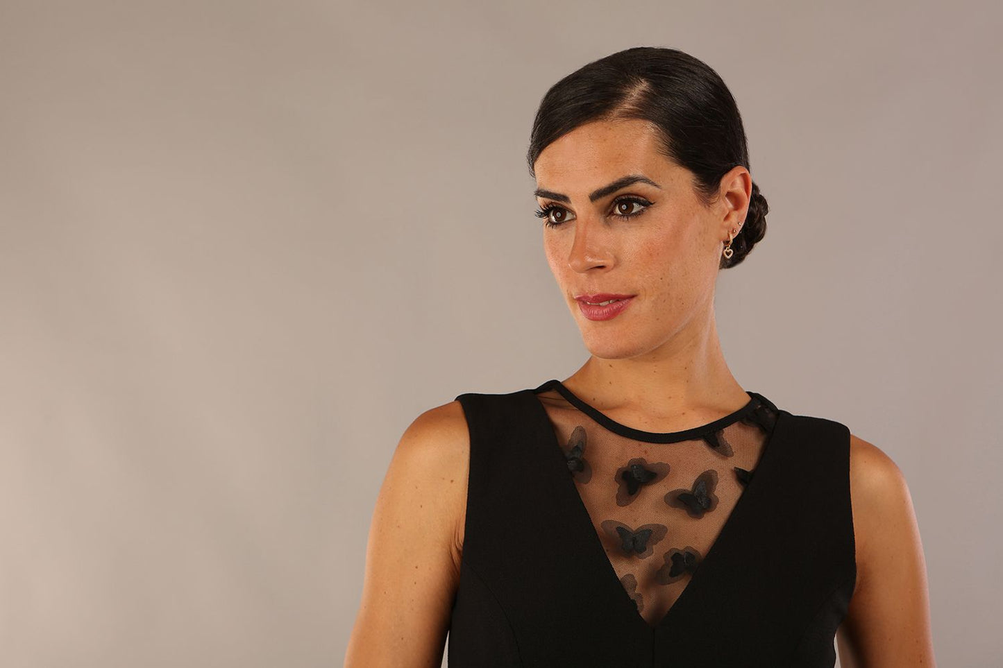 model wearing a Diva Catwalk Patina A-line Swing Sleeveless dress with v-neckline with butterfly detail in Black close up