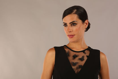 model wearing a Diva Catwalk Patina A-line Swing Sleeveless dress with v-neckline with butterfly detail in Black close up