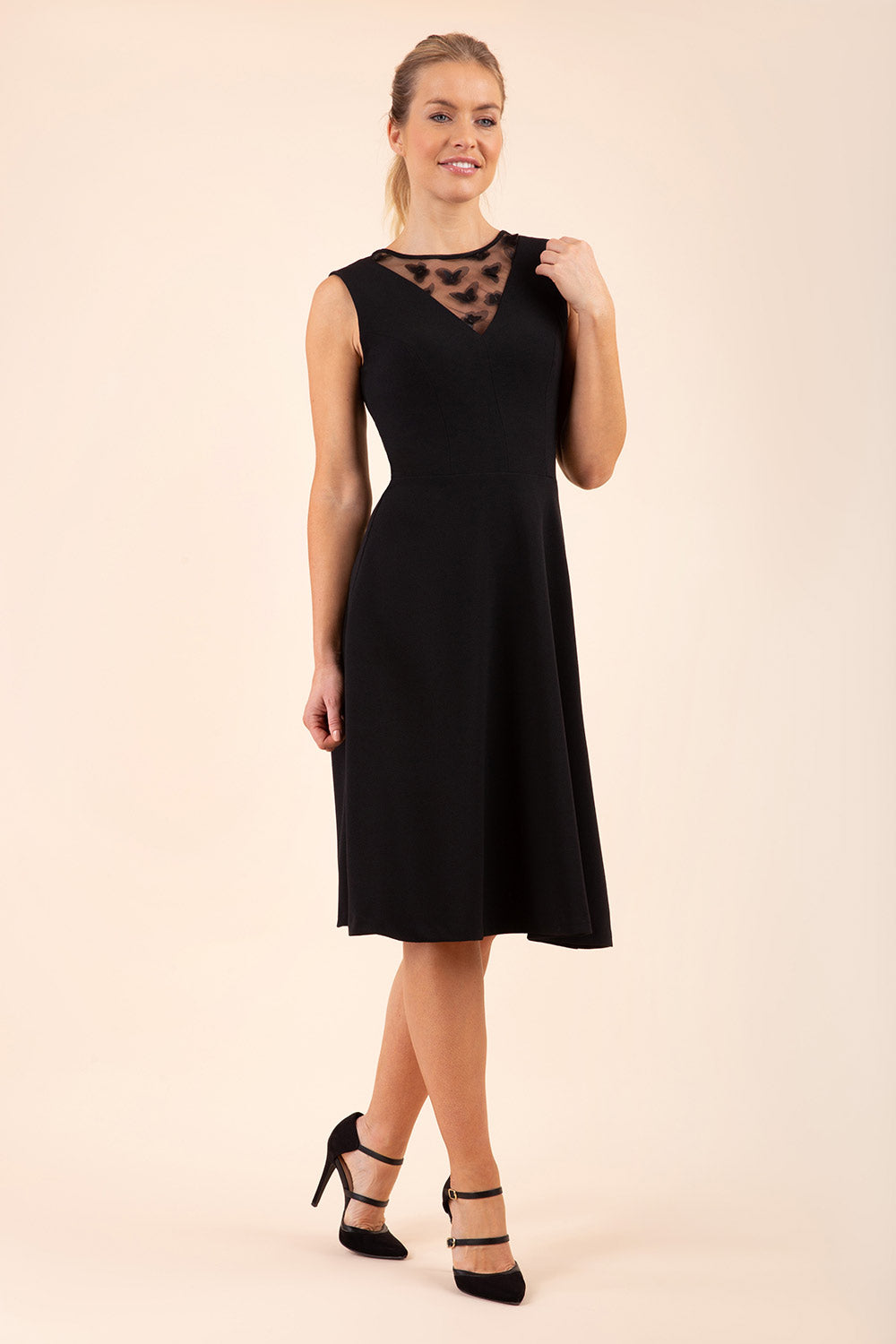 model wearing a Diva Catwalk Patina A-line Swing Sleeveless dress with v-neckline with butterfly detail in Black close up