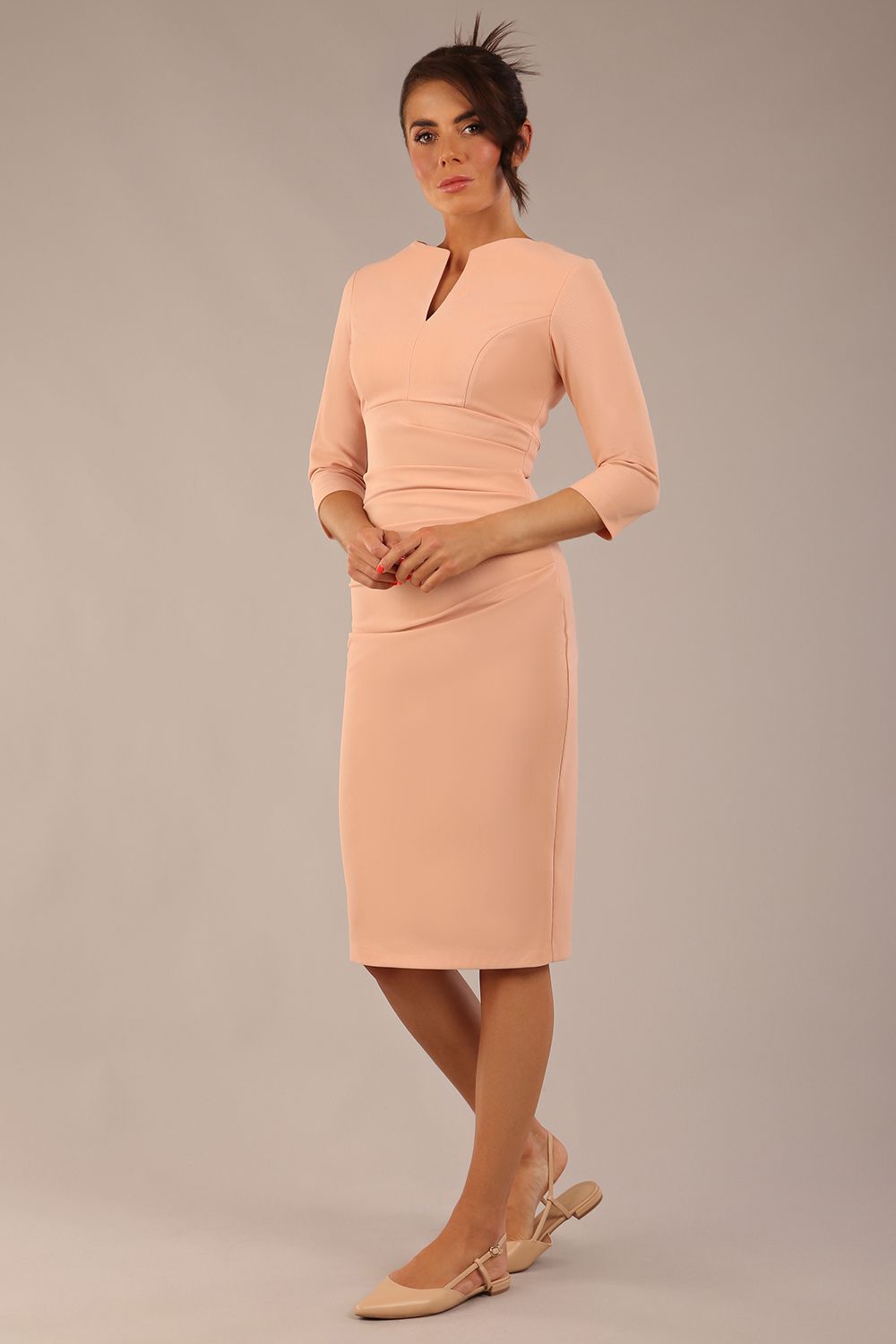 brunette model wearing a Diva Catwalk pencil three quarter sleeve dress with a split neckline and pleating across the tummy and round neck in almond mousse colour front
