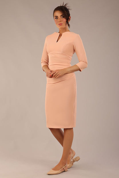 brunette model wearing a Diva Catwalk pencil three quarter sleeve dress with a split neckline and pleating across the tummy and round neck in almond mousse colour front