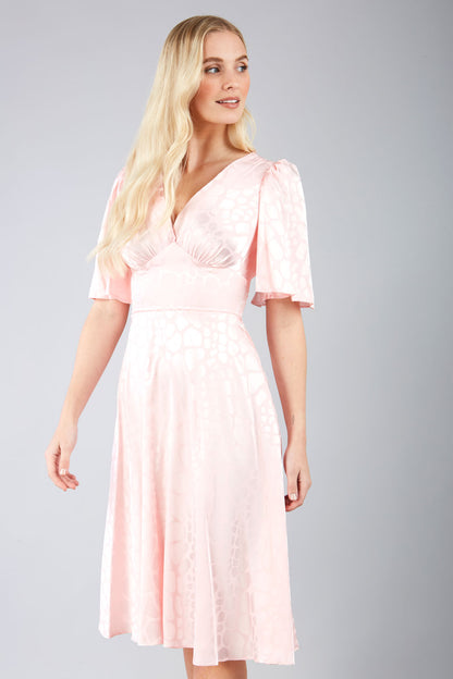 model wearing diva catwalk cambrian satin swing dress with bell short sleeve wide asymmetric waistband and pleating under bust in pink front