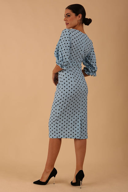 Blonde model wearing Diva Catwalk Palacio Pencil dress v neckline and pleating across the tummy with puffed short sleeves in blue polka dot front