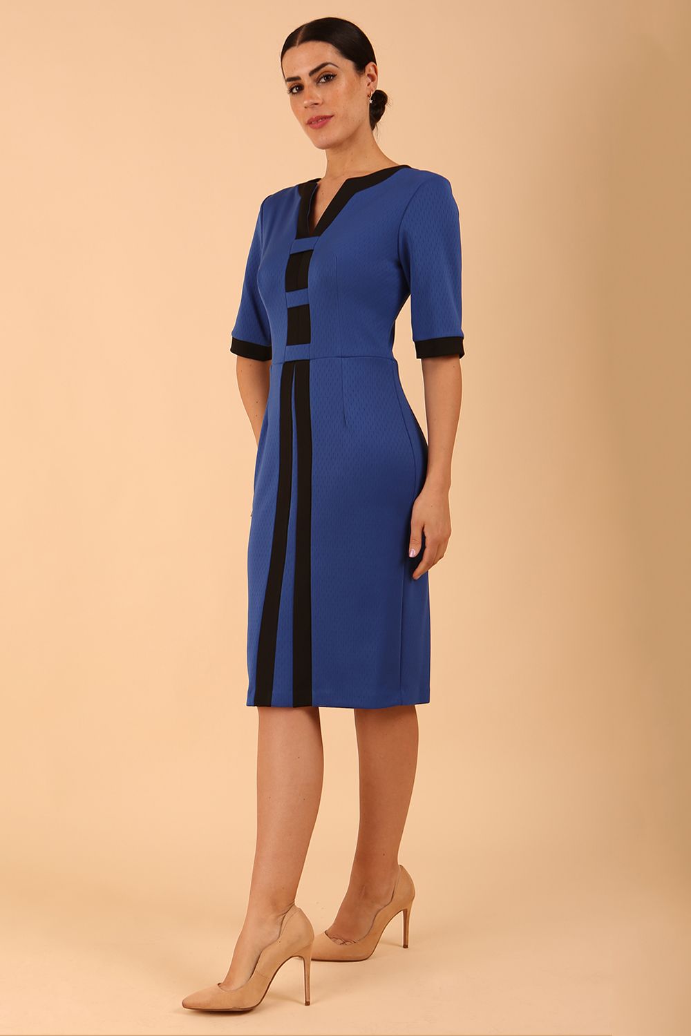 brunette model wearing Diva catwalk goggle pencil dress with short sleeve and v-neckline with contrasted design across body in princess blue front