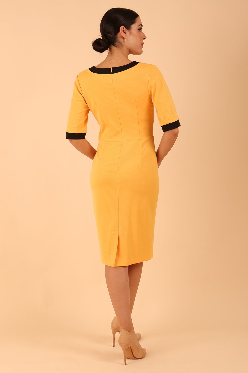 brunette model wearing Diva catwalk goggle pencil dress with short sleeve and v-neckline with contrasted design across body in yellow front