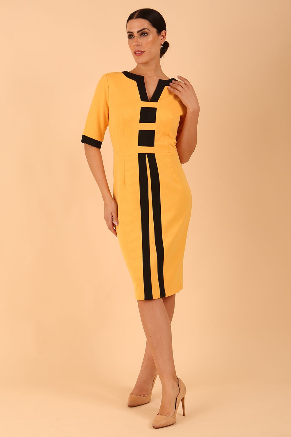 brunette model wearing Diva catwalk goggle pencil dress with short sleeve and v-neckline with contrasted design across body in yellow front