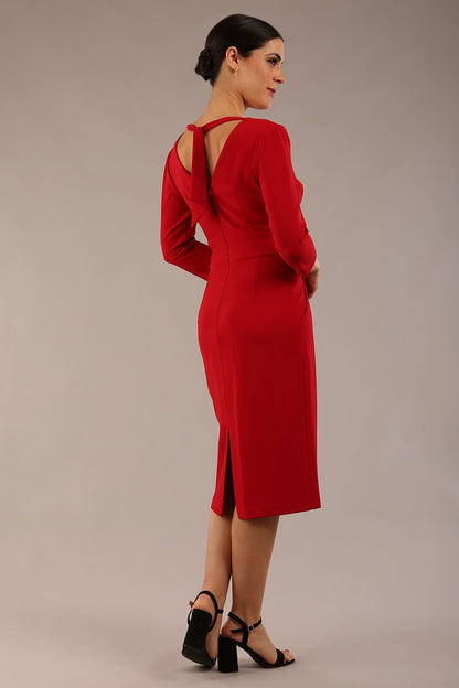 brunette model wearing diva catwalk wimpole a-line flattering dress with lowered v-neck and three quarter sleeve and cinching waistband and widened skirt with pleating in scarlet red front