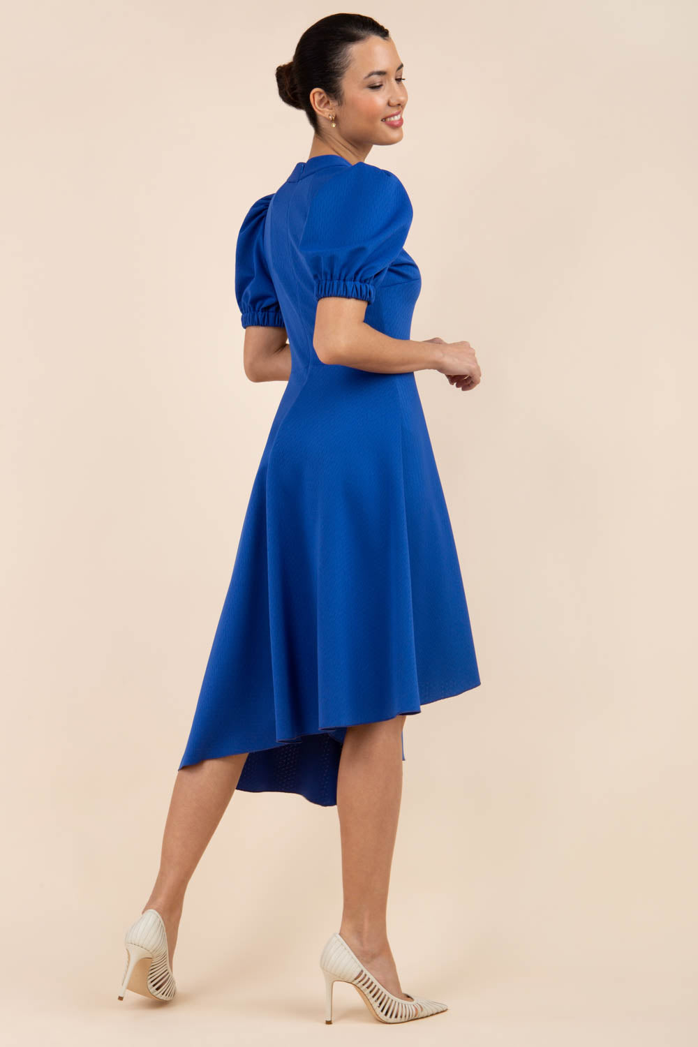 brunette model wearing diva catwalk ola swing dress with puffed oversized sleeves and asymmetric swing skirt with rounded high neck in blue front