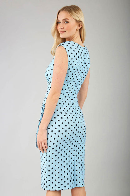 Brunette model wearing Diva Catwalk Perry Polka Dot Pencil Sleeveless Dress with tie detail on a side and rounded neckline in sky blue front