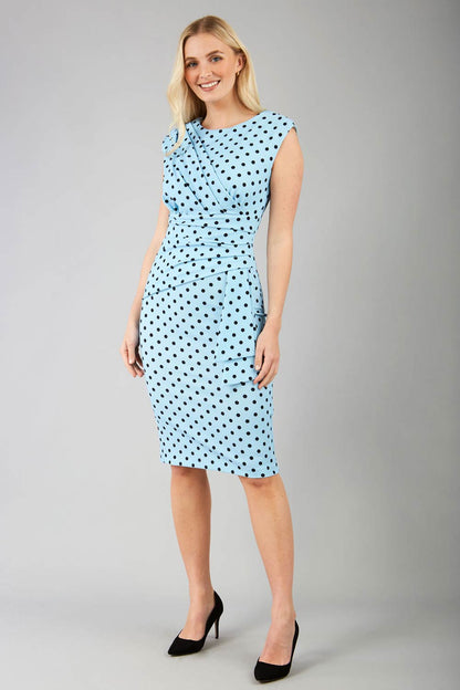 Brunette model wearing Diva Catwalk Perry Polka Dot Pencil Sleeveless Dress with tie detail on a side and rounded neckline in sky blue front
