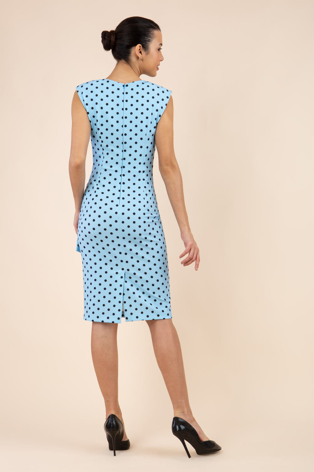 Brunette model wearing Diva Catwalk Perry Polka Dot Pencil Sleeveless Dress with tie detail on a side and rounded neckline in sky blue front