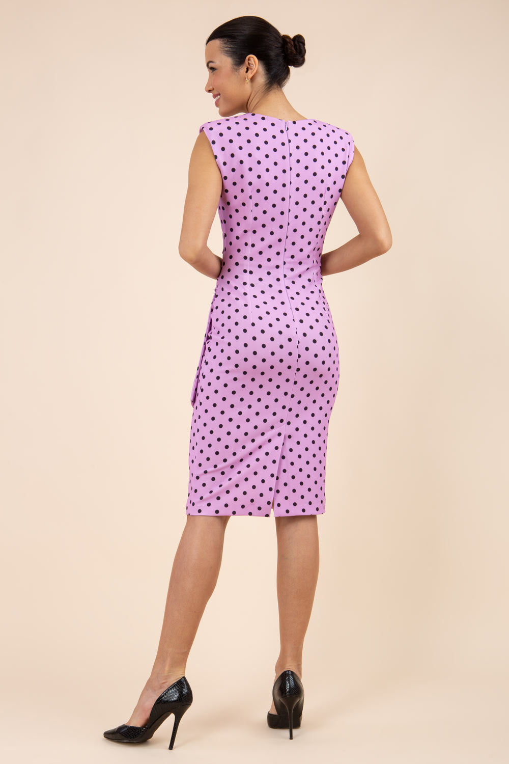Brunette model wearing Diva Catwalk Perry Polka Dot Pencil Sleeveless Dress with tie detail on a side and rounded neckline in pink front