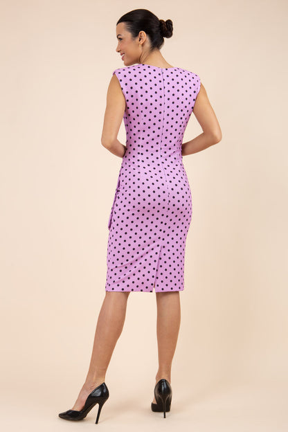 Brunette model wearing Diva Catwalk Perry Polka Dot Pencil Sleeveless Dress with tie detail on a side and rounded neckline in pink front