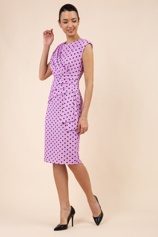 Brunette model wearing Diva Catwalk Perry Polka Dot Pencil Sleeveless Dress with tie detail on a side and rounded neckline in pink front